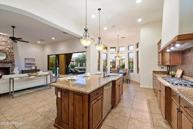 kitchen featuring ceiling fan, decorative backsplash, stainless steel appliances, a sink, and wall chimney exhaust hood