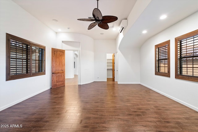 spare room featuring baseboards, a wall mounted air conditioner, a ceiling fan, and wood finished floors