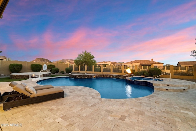 pool at dusk featuring a pool with connected hot tub, a fenced backyard, and a patio area