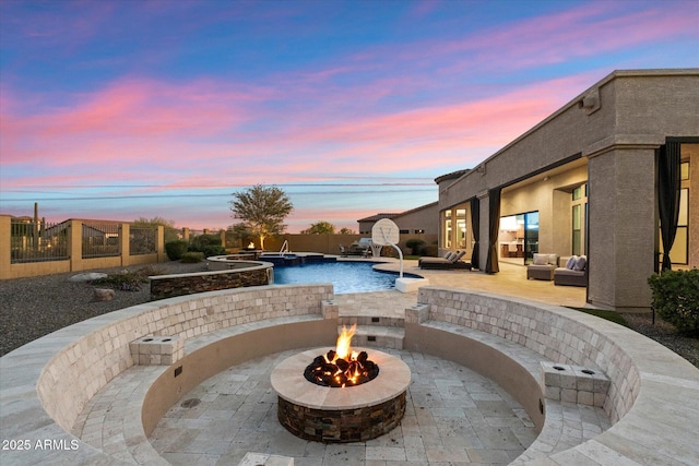 view of swimming pool with a patio, a pool with connected hot tub, an outdoor living space with a fire pit, and fence