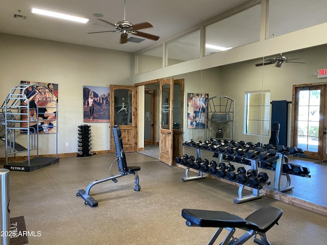 workout area with visible vents, baseboards, a ceiling fan, and a towering ceiling
