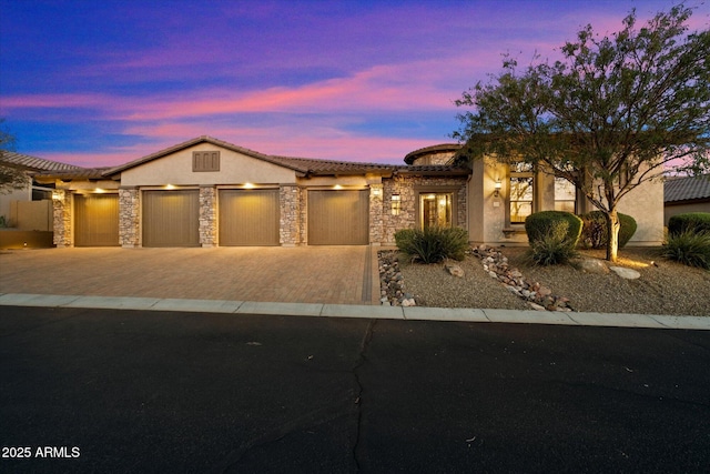 view of front of house featuring a tile roof, an attached garage, driveway, and stucco siding
