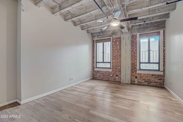 unfurnished room featuring ceiling fan, light hardwood / wood-style flooring, plenty of natural light, and brick wall