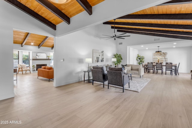 living room featuring beam ceiling, ceiling fan, light hardwood / wood-style floors, and wooden ceiling