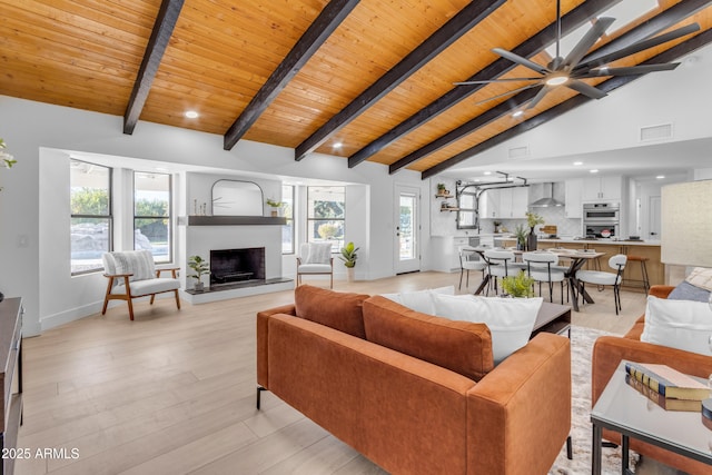 living room with a healthy amount of sunlight, beam ceiling, light hardwood / wood-style flooring, and wood ceiling