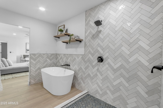 bathroom featuring hardwood / wood-style floors, tile walls, and a tub to relax in