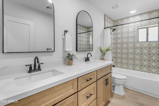 full bathroom featuring hardwood / wood-style flooring, shower / bath combination with curtain, vanity, and toilet