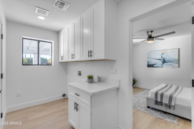 laundry room featuring washer hookup, ceiling fan, cabinets, and light wood-type flooring