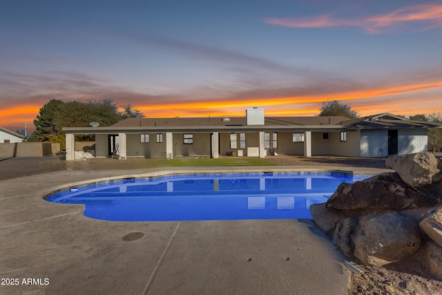 pool at dusk featuring a patio area