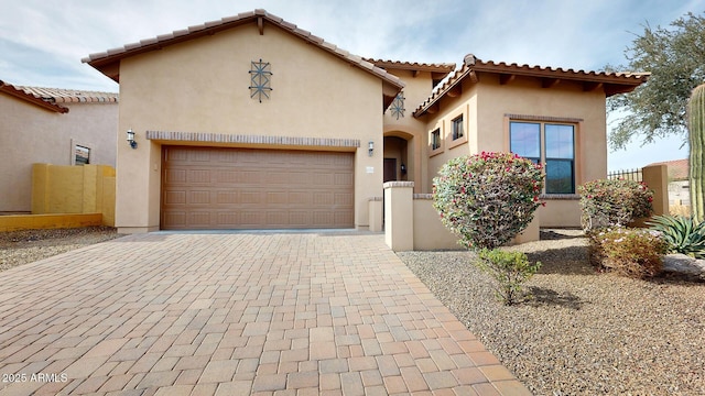 mediterranean / spanish-style house with stucco siding, a tile roof, decorative driveway, and a garage