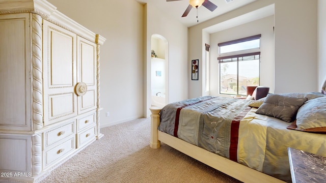 bedroom featuring a ceiling fan, baseboards, light colored carpet, and ensuite bathroom