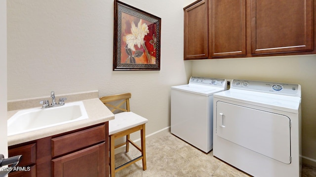 washroom featuring a sink, baseboards, cabinet space, and washing machine and clothes dryer