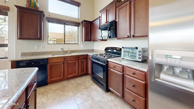 kitchen featuring light stone counters, a toaster, light tile patterned flooring, a sink, and black appliances