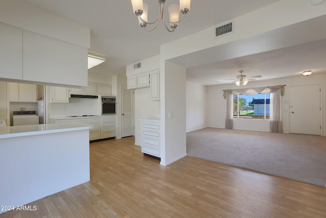 kitchen with light hardwood / wood-style floors, decorative light fixtures, black oven, white cabinets, and ceiling fan with notable chandelier