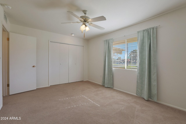 unfurnished bedroom featuring ceiling fan, light colored carpet, and a closet