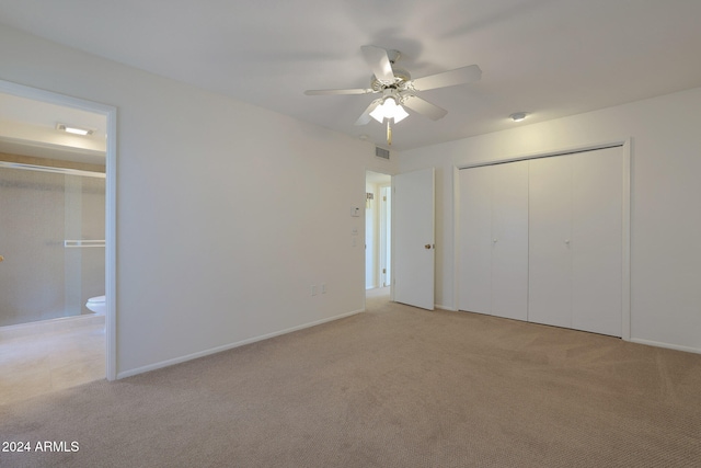 unfurnished bedroom with ensuite bath, ceiling fan, a closet, and light colored carpet