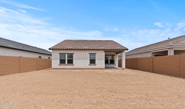 42405 W Peters Dr, Maricopa, AZ 85138 - back of house featuring a tiled roof, a fenced backyard, stucco siding, and a patio area