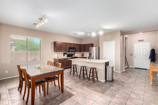 tiled dining room featuring rail lighting and sink