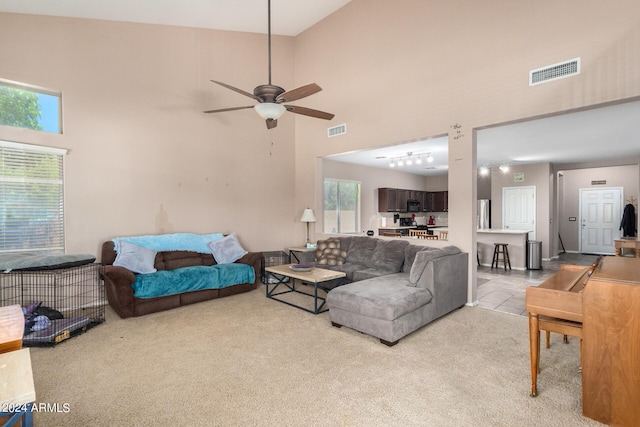 carpeted living room with ceiling fan and high vaulted ceiling