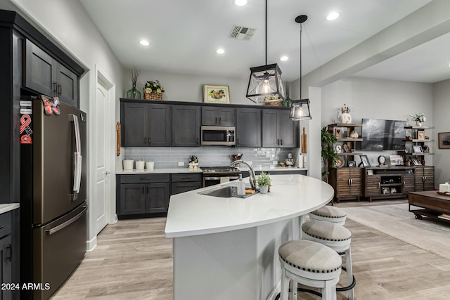 kitchen with pendant lighting, light wood-type flooring, stainless steel appliances, and sink