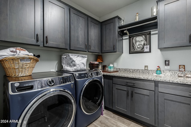 washroom featuring cabinets, light hardwood / wood-style floors, and washing machine and clothes dryer