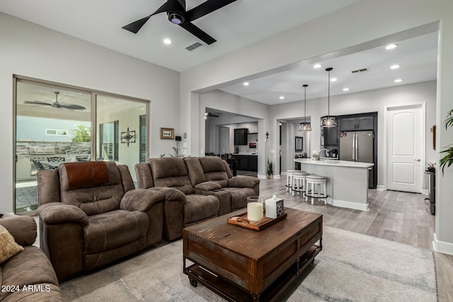 living room featuring sink, ceiling fan, and light hardwood / wood-style flooring