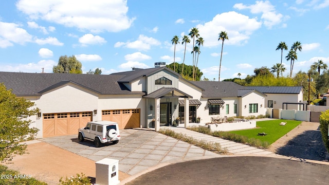 modern inspired farmhouse featuring a garage, driveway, a front yard, and fence