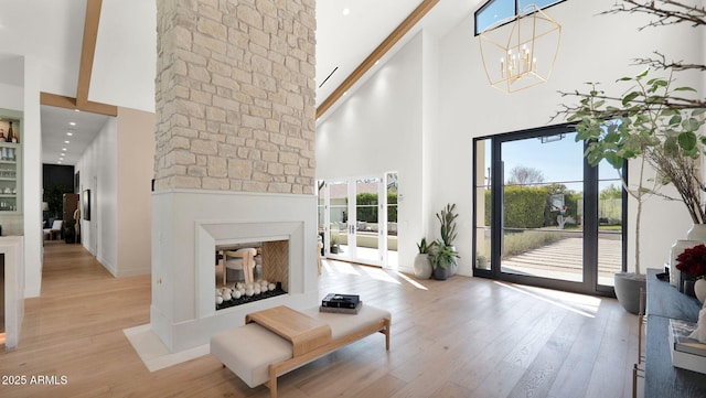 living room with an inviting chandelier, a high ceiling, and light wood finished floors