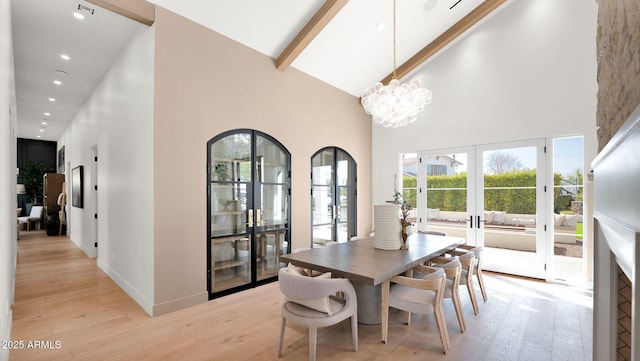 dining room featuring beam ceiling, french doors, high vaulted ceiling, and light wood-type flooring