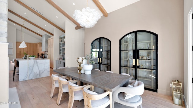 dining area featuring beamed ceiling, light wood-style floors, a chandelier, and high vaulted ceiling