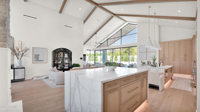 kitchen with light wood-type flooring, a large island, beamed ceiling, and open floor plan