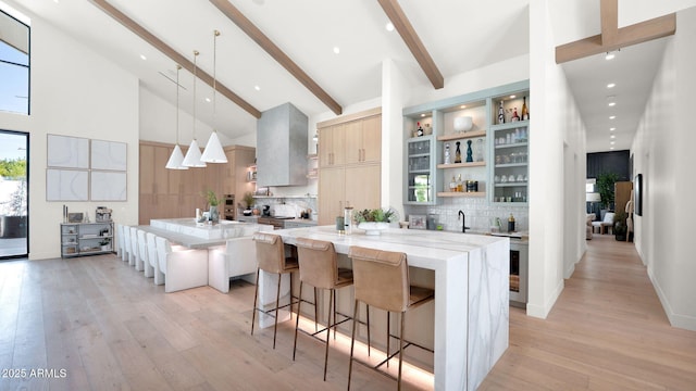 kitchen with a large island, beam ceiling, modern cabinets, and light wood-style floors