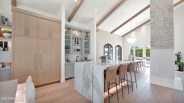 kitchen featuring light brown cabinets, light stone countertops, beamed ceiling, light wood-style floors, and open shelves