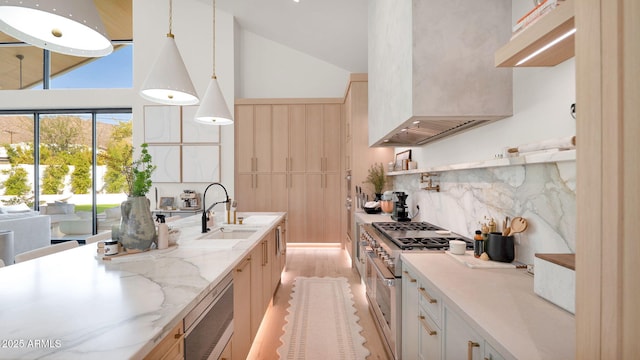 kitchen with a sink, backsplash, appliances with stainless steel finishes, light wood finished floors, and light stone countertops