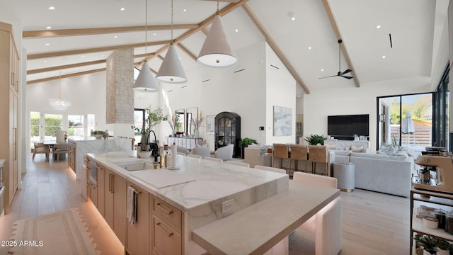 kitchen with beam ceiling, open floor plan, light brown cabinetry, and a sink