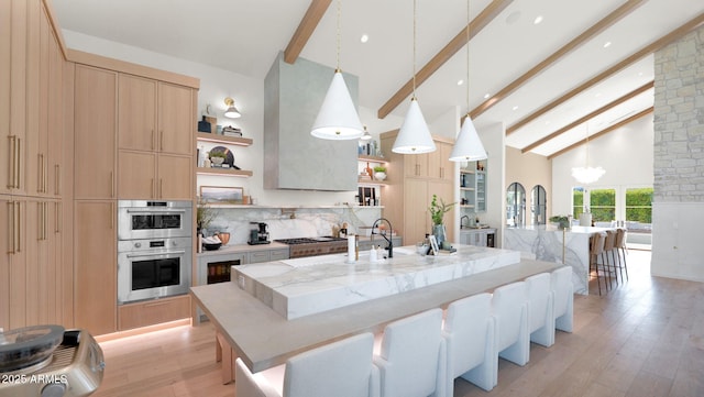 kitchen featuring beam ceiling, high vaulted ceiling, light brown cabinetry, open shelves, and appliances with stainless steel finishes