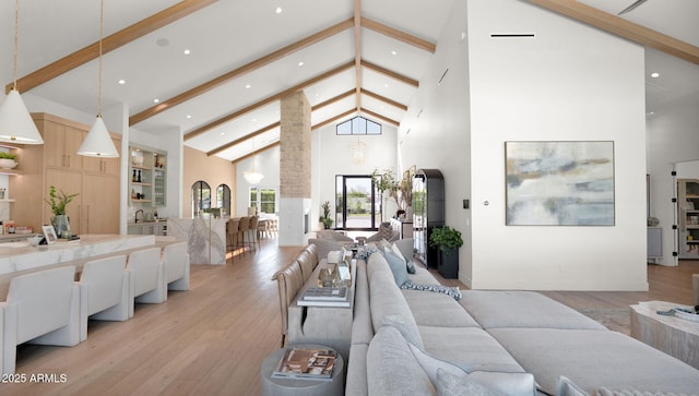 living area with light wood-type flooring, beamed ceiling, and high vaulted ceiling