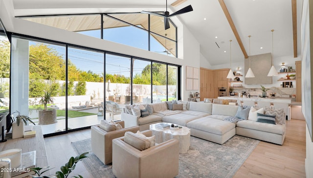 living area with light wood-type flooring, beam ceiling, high vaulted ceiling, and a ceiling fan