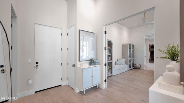 foyer featuring light wood-style flooring and a towering ceiling