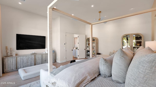 bedroom featuring recessed lighting, french doors, wood finished floors, and a towering ceiling