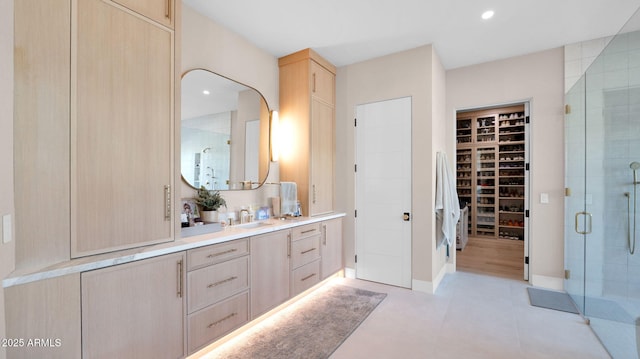 full bathroom with a walk in closet, a stall shower, recessed lighting, baseboards, and vanity