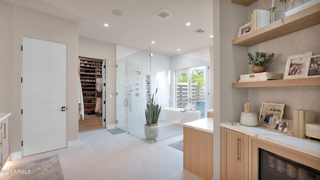 bathroom featuring visible vents, a walk in closet, recessed lighting, a shower stall, and a soaking tub