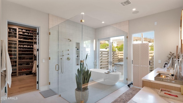 bathroom featuring visible vents, a freestanding tub, recessed lighting, a shower stall, and a walk in closet