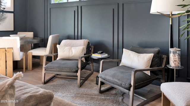 sitting room featuring a decorative wall and wood finished floors