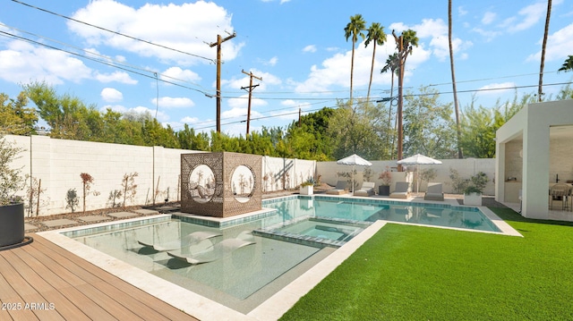 view of swimming pool with a lawn, a pool with connected hot tub, and a fenced backyard