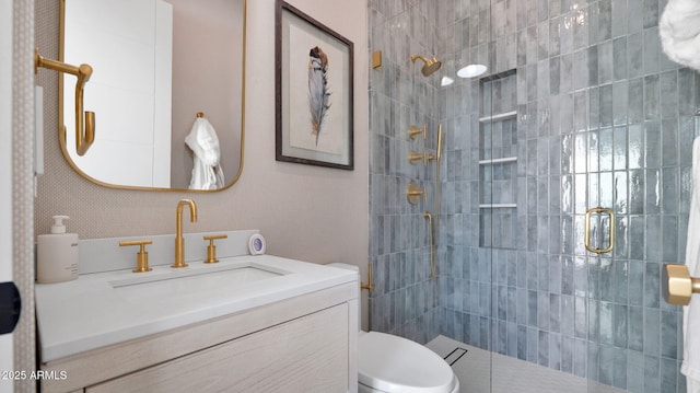 full bathroom featuring toilet, tiled shower, and vanity