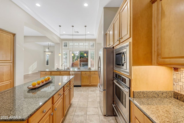 kitchen with a warming drawer, stainless steel appliances, tasteful backsplash, a kitchen island, and dark stone counters