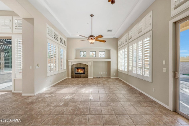 unfurnished living room with visible vents, baseboards, a tiled fireplace, ceiling fan, and tile patterned floors