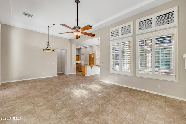 unfurnished living room with ceiling fan, visible vents, and baseboards