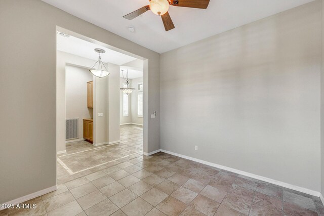 unfurnished room with baseboards, visible vents, and ceiling fan